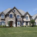 A large brick home with a grassy lawn in front of it.