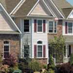A large house with many windows and flowers in the front yard.