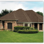 A large brick house with a green lawn in front of it.