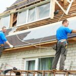 Workers installing roofing on a house.