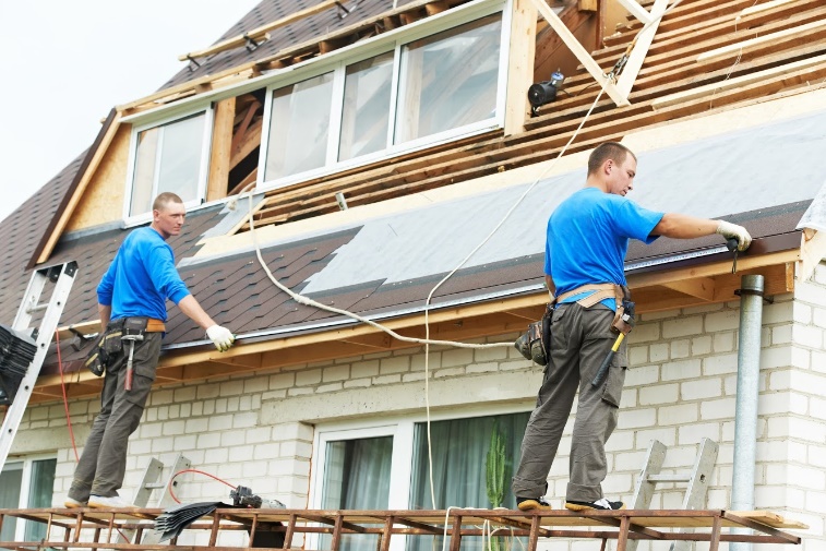 Workers installing roofing on a house.