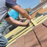 Workers installing wooden beams on roof.