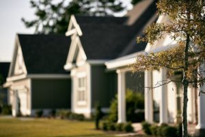 Suburban houses with trees and green lawn.
