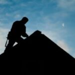 Silhouette of person working on a roof.
