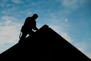 Silhouette of person working on a roof.