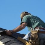 Roofer installing shingles on a house roof.