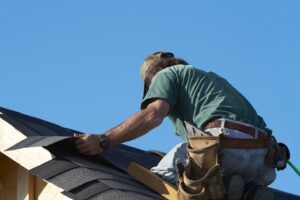 Roofer installing shingles on a house roof.