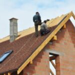 Workers repairing roof of a house.