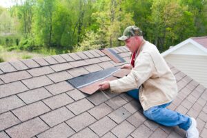 Man repairing roof with shingles.