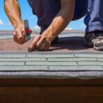 Person installing shingles on a roof.