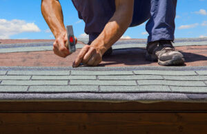 Person installing shingles on a roof.