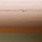 Water droplet on wooden ceiling surface.
