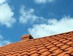 Red tiled roof under blue sky.