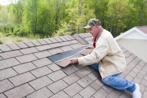 Man repairing roof shingles on house.