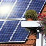Solar panels on roof with flowers nearby.