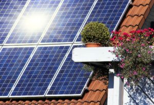 Solar panels on roof with flowers nearby.