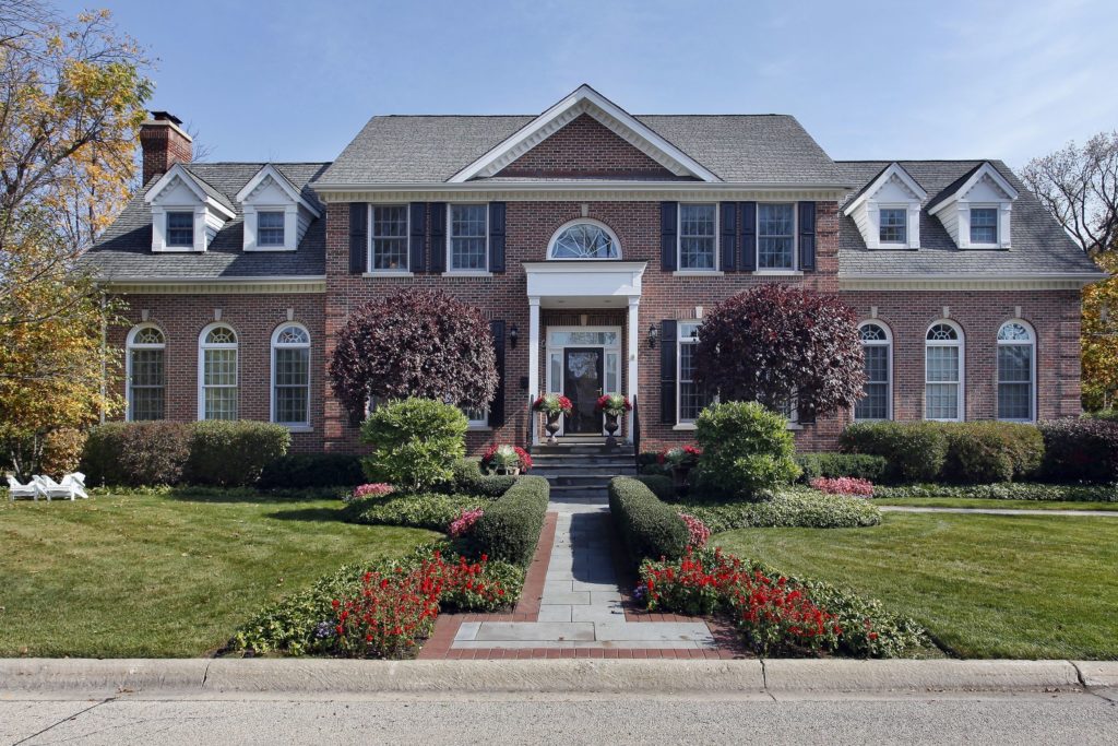 Elegant brick mansion with symmetrical landscaping and a central water feature.
