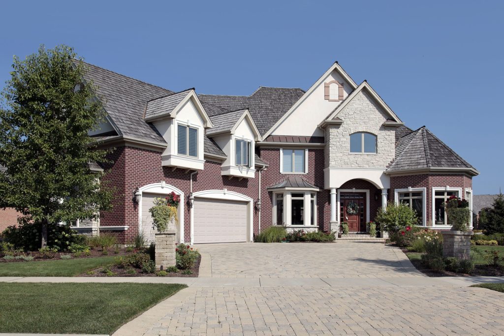 Elegant two-story brick house with a spacious driveway and large windows.