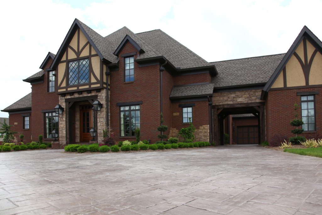 Large two-story brick house with Tudor-style accents and spacious driveway.
