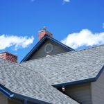 Close-up of a house roof with a weather vane against a blue sky.