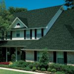 A house with a complex roof design and lush green landscaping.