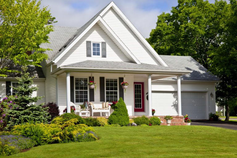 Charming white house with a front porch and well-kept lawn.