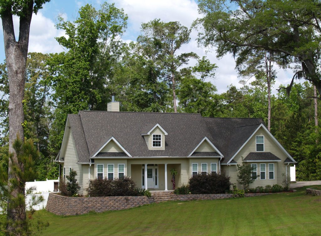 A charming single-story house with a well-kept lawn and surrounding trees.
