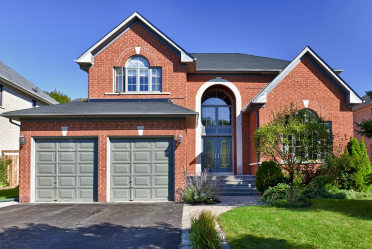 A modern two-story brick house with a double garage and well-kept lawn.
